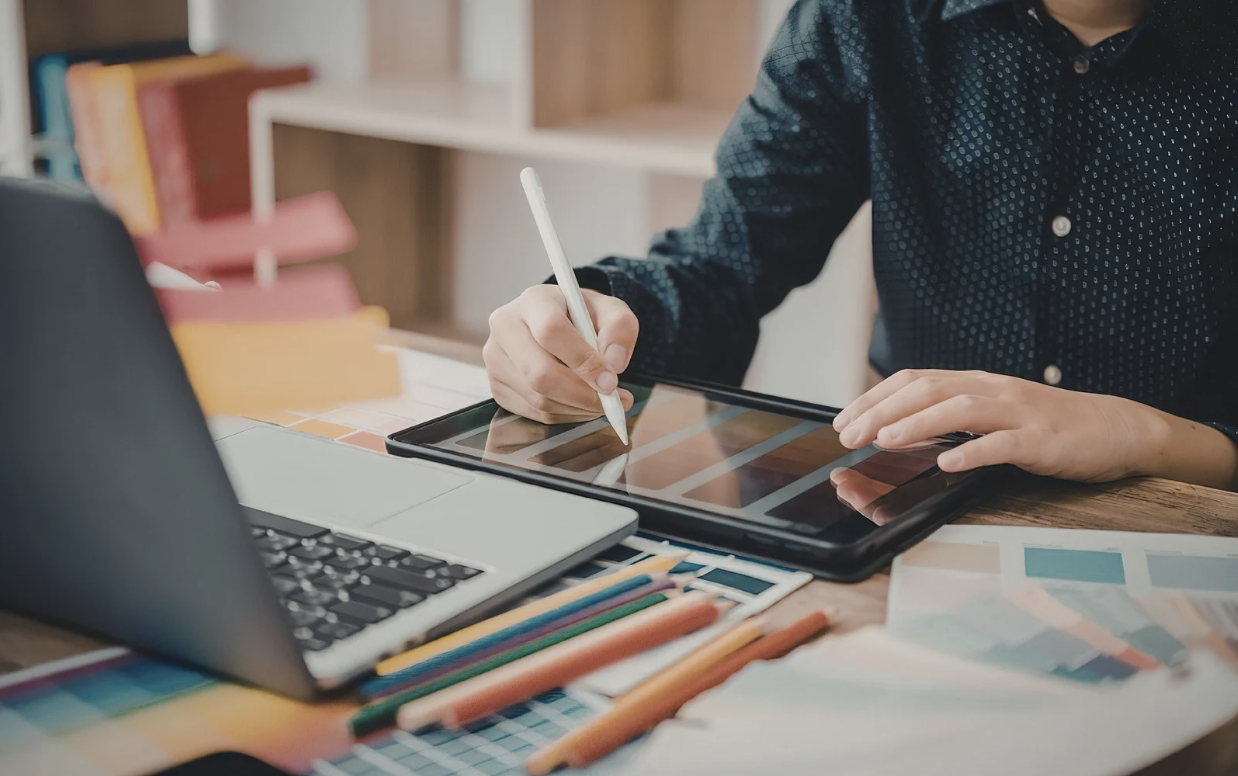 Graphiste travaillant sur l'élaboration d'une charte graphique sur tablette et ordinateur portable